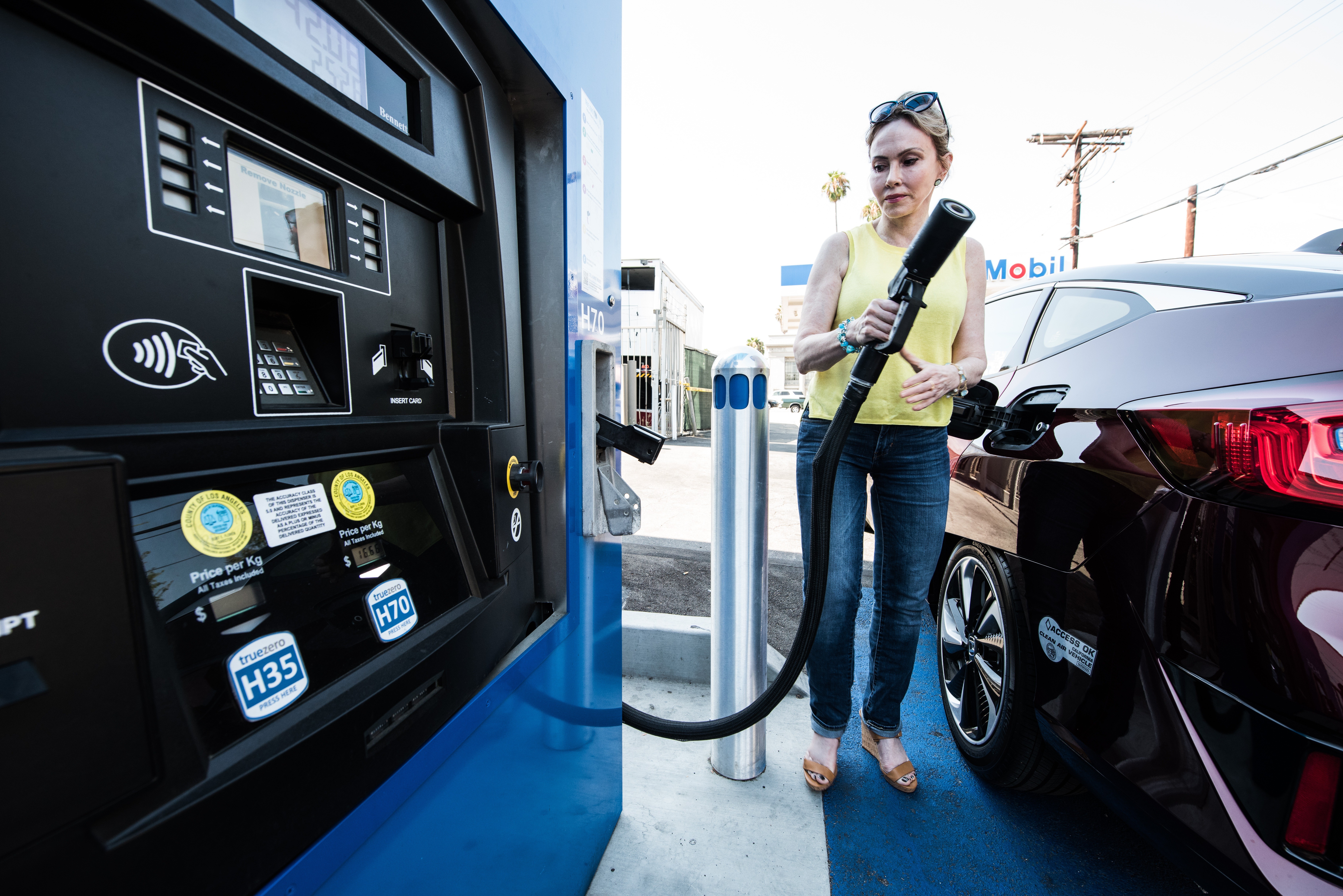 A photo of a woman fueling up her fuel cell electric vehicle.