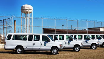 Photo of several propane vans parked outside a fenced prison facility.