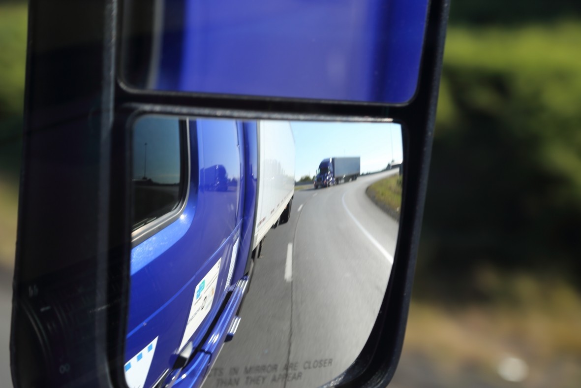 Photo of tractor-trailers reflected in a side view mirror.