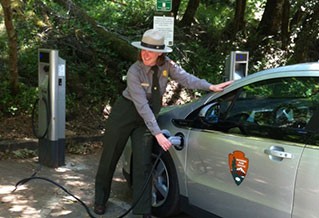 Photo of a woman plugging in an electric vehicle