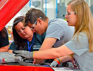 This photo shows three students from Rose-Hulman Institute of Technology working under the hood of their car.