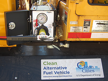 A close-up photo of a compressed natural gas truck with a white Clean Cities sticker refueling at a CNG station.