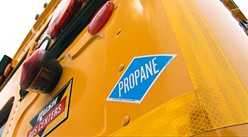 A photo of an orange school bus with a propane sticker on the back.