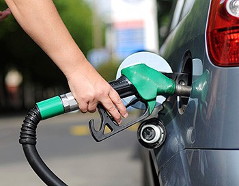 Photo of a person's hand using a green fuel nozzle to fill their car with biofuel.