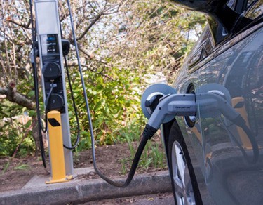 Photo of a car being recharged in a wooded area.