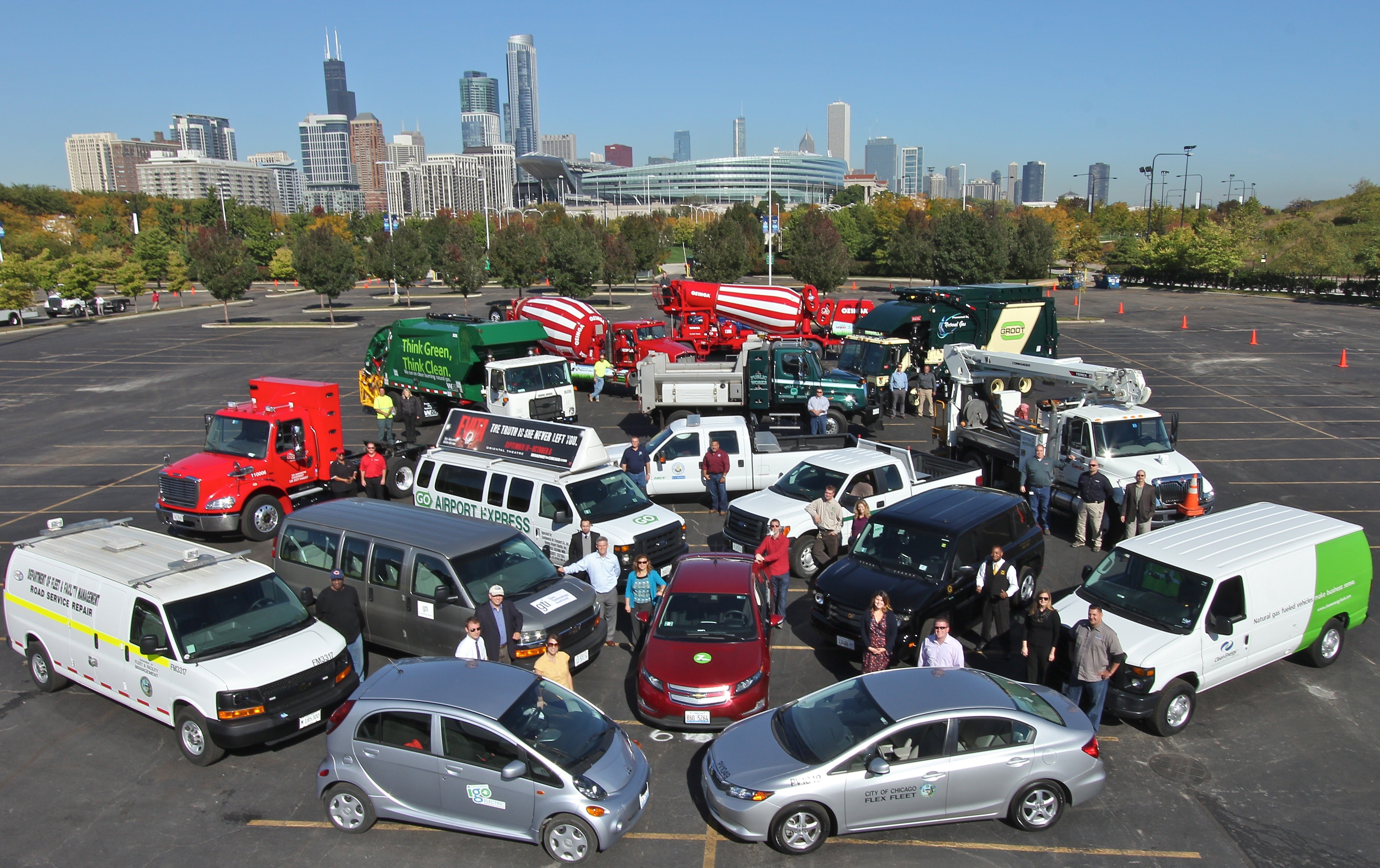 A group of alternative fuel vehicles in a parking lot with the Chicago skyline in the background